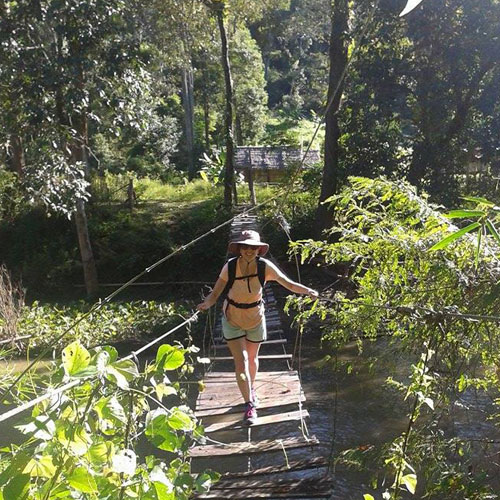 Hiking crossing river on wooden bridge