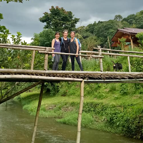 Hiking crossing river on wooden bridge